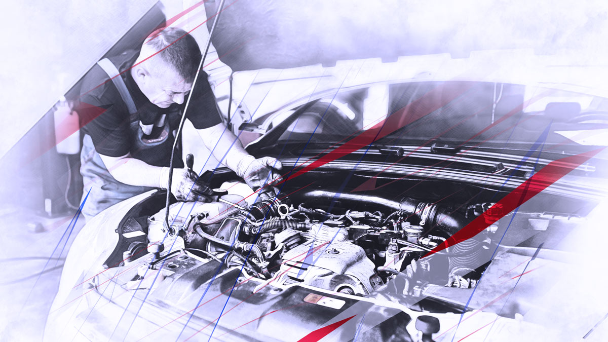 Ein Fahrzeugmechaniker inspiziert mit Werkzeugen und den Händen den Motorraum eines Fahrzeuges